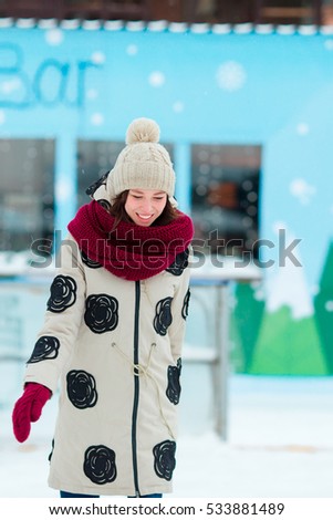 Happy young girl skating on ice rink outdoors