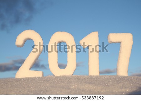 Numbers 2017 from snow crust on snowdrift against blue sky