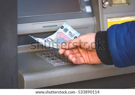 Male hand taking 20 Euro banknotes from bank machine