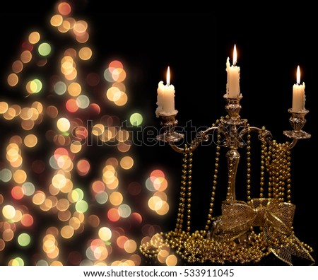 Vintage candlestick with burning candles and Christmas Golden ornaments on black background.
