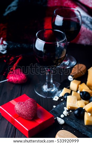 two glasses of wine with a blanket and a heart with a gift on Valentine's Day