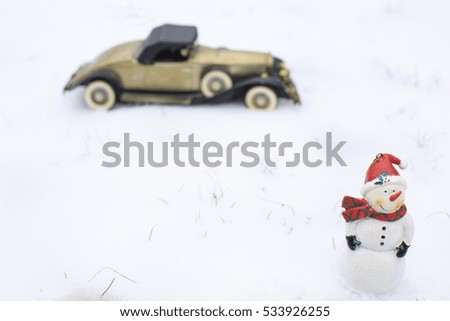 Antique toy car on snowy winter. Extreme shallow depth of field with selective focus on the snowman.