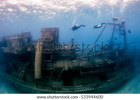 SCUBA divers around a huge underwater shipwreck Royalty-Free Stock Photo #533944600