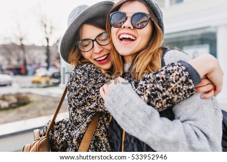 Happy brightful positive moments of two stylish girls hugging on street in city. Closeup portrait funny joyful attarctive young women having fun, smiling, lovely moments, best friends Royalty-Free Stock Photo #533952946