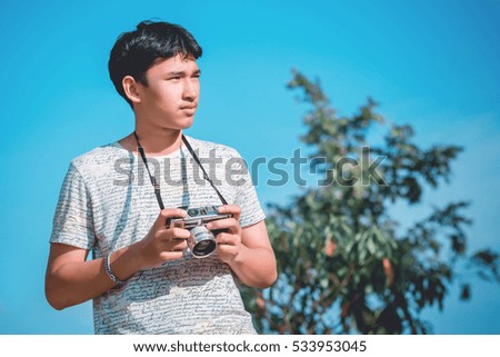 Lifestyle portrait of  young photographer with vintage camera taking photo.