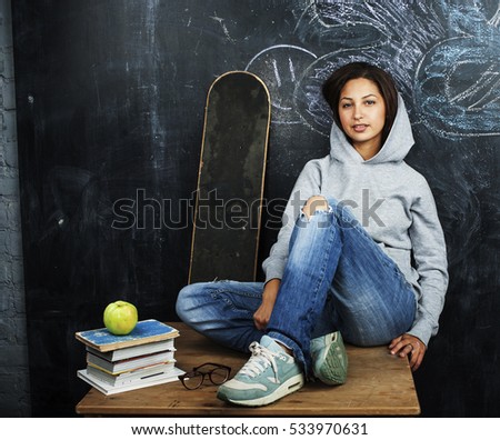 young cute teenage girl in classroom at blackboard seating on ta