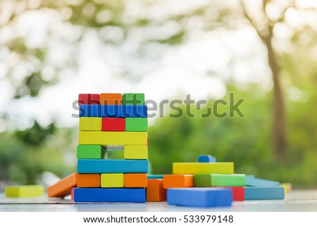 Colorful Wooden block Stack tower game for children playing on wood table in public park under morning sun light, with copyspace, Learning and Education Background concept