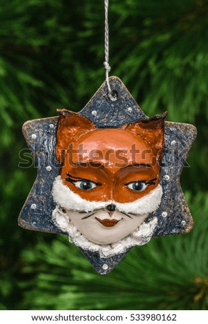 Festive decoration in the shape of a foxy mask, on a Christmas tree background