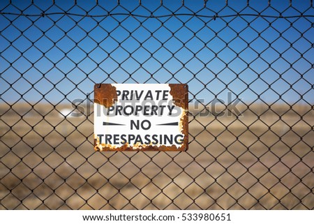 Private Property - No Trespassing Sign, With Chain Link Fence, Rust and Empty Field.