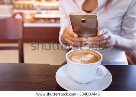 Asian women take a photo to coffee from his mobile phone camera,Focus on the cup of coffee
