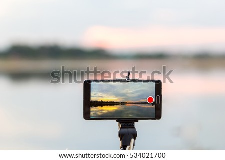 using smart phone take a photo of sunset landscape on lake