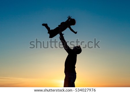 Father and son playing in the park at the sunset time. People having fun on the beach. Concept of friendly family and of summer vacation.