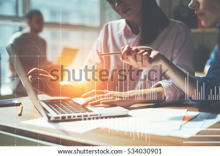 Team working on a project in loft office. Two women discussing marketing plan. Laptop and paperwork on the table. Statistic graph overlay, icon innovation interface Royalty-Free Stock Photo #534030901