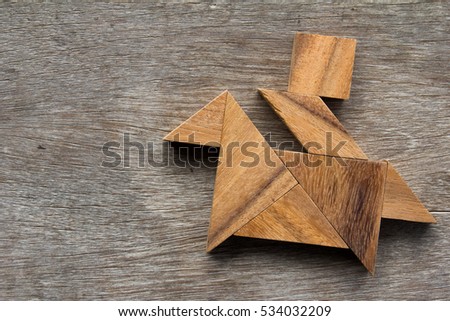 Tangram puzzle as man ride the horse shape on old wood background
