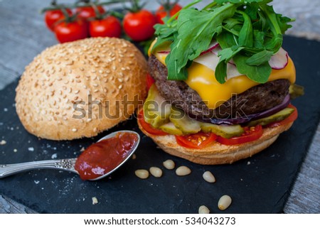 Homemade beef burger on a black slate background.