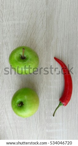 a red hot chili pepper and two green apples