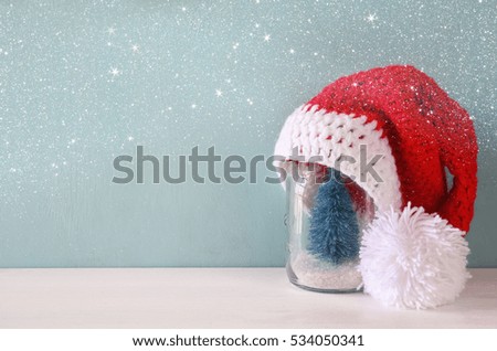 Image of cute knitted santa hat on mason jar with christmas tree

