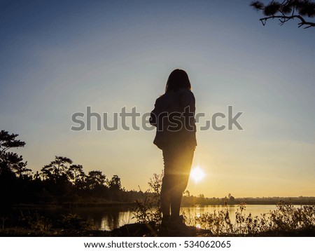 women looked at sunrise near the pond ,Silhouette image