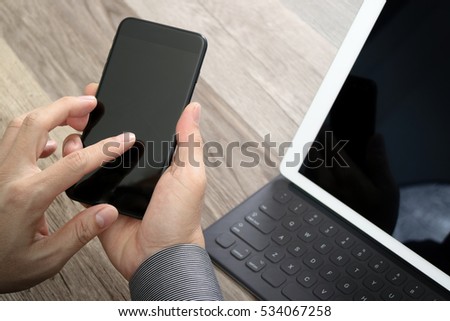 Hand using mobile payments online shopping,omni channel,icon customer network,in modern office on wooden desk, blank interface screen,filter effect