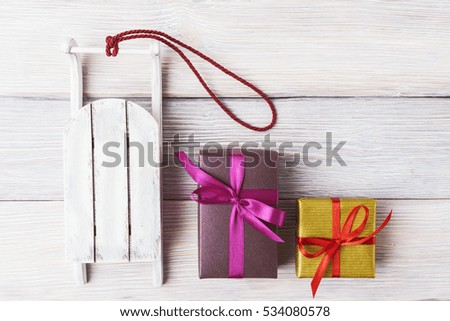 Gift boxes and Santa's sled over vintage wooden background
