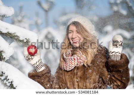 Girl with a Christmas toy enjoying the snow in the forest. Sunny mood. Young woman in the coniferous forest.