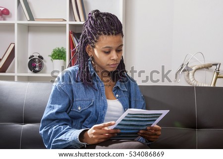 young woman with looking at the paper, bills, receipt or invoice and the laptop