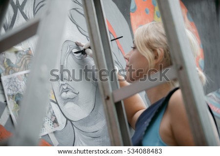 Cheerful young woman painting on the wall.