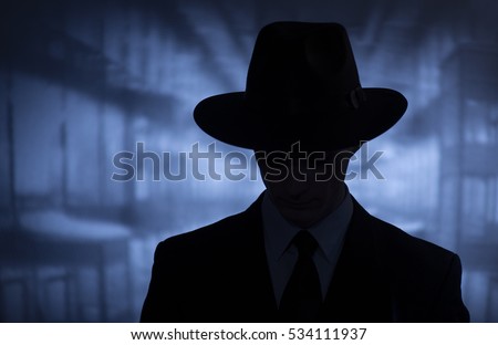Silhouette of a mysterious man in a vintage style wide brimmed hat in a close up head and shoulders portrait Royalty-Free Stock Photo #534111937
