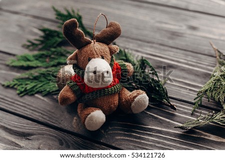 reindeer toy and christmas fir branches  on rustic wooden background with space for text. seasonal greetings concept. preparation for winter holidays