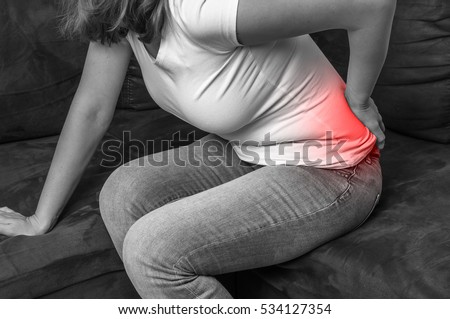 Woman with back pain holding aching part - black and white photo