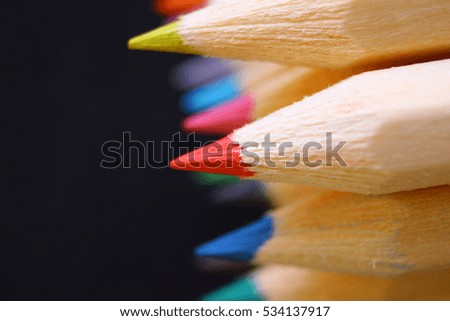 Macro of group of white wooden crayons with different colors on a black background 