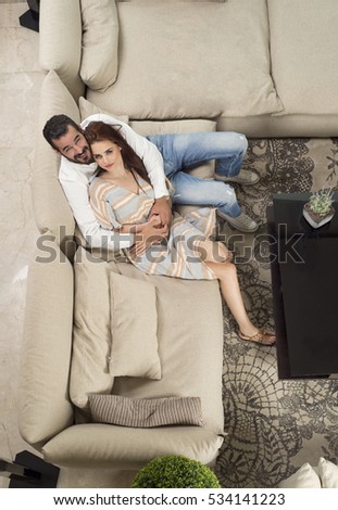 Top view of a beautiful Young Couple Sitting on a Couch, Couple in love sitting in a modern interior