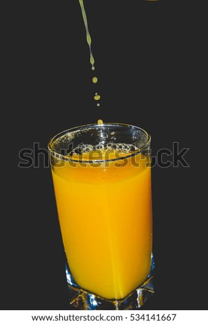 pouring fresh orange juice on a black background
