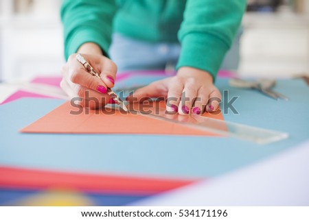 Young woman make scrapbook of the papers on the table using antique tools for cutting paper. Hand made photo album.Shallow depth of field