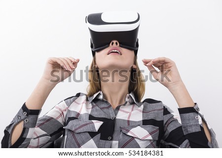 Close up of a young woman with long blond hair wearing virtual reality glasses and looking upwards