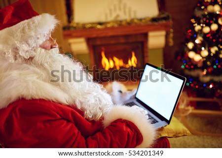 Santa Claus reading email on laptop with Christmas requesting or wish list
