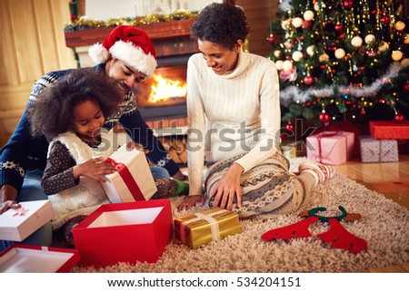 Happy afro American family in Christmas morning opening present
