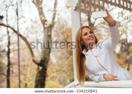 Happy fashion woman in fall autumn park taking selfie self photo picture.