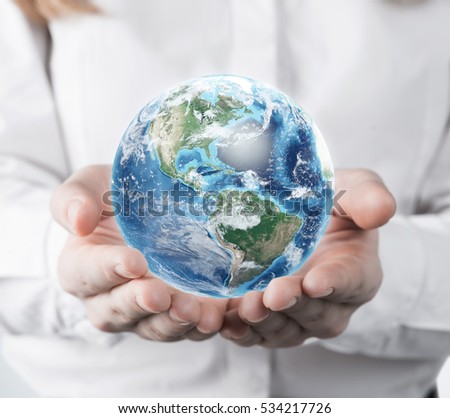 Close up of a woman in a white blouse is holding a planet in her hands. Concept of a small world. Elements of this image furnished by NASA