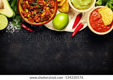 Mexican food concept: tortilla chips, guacamole, salsa, chilli with beans and fresh ingredients over vintage rusty metal background. Top view Royalty-Free Stock Photo #534220576