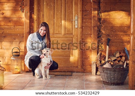 Cute girl with beautiful dog in front of wooden house