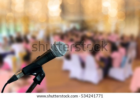 Microphone on stage in conference hall. Microphone on boom stand  ready for the meeting ,blurred background group of people sitting around table. Let's talk