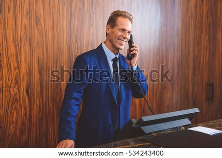 Senior manager answering call in lobby Royalty-Free Stock Photo #534243400