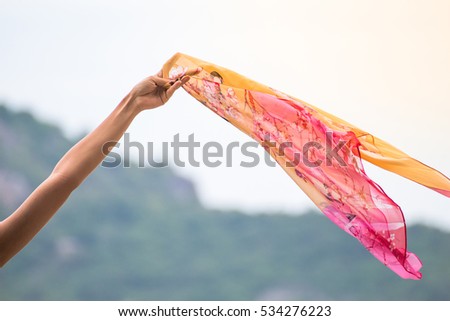 Beautiful young woman with flying scarf on beach,Carefree girl seaside holding scarf fluttering in the wind.
