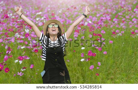 beautiful girl in a cosmos flower field at sun light Outdoors enjoying nature, raising hands.. concept of freedom