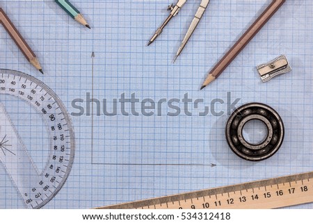 Measuring tools above  blue graph paper.