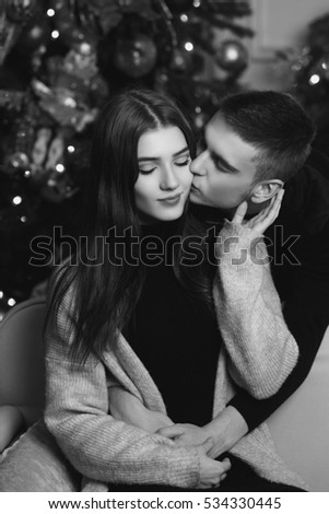 Young romantic cute couple staying at home and enjoying time together. Lovers hugging in christmas decorated interior