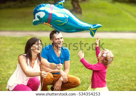 happy mother and father with little daughter in park
