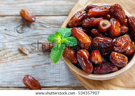 Dried date and green mint in a bowl on old wooden table close up. Royalty-Free Stock Photo #534357907