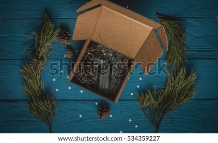 black vaporizer out of a gift box with pine cones and pine branches